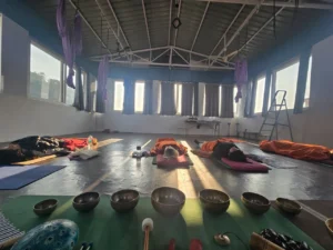Sound bath meditation session with participants lying down surrounded by singing bowls in Rishikesh