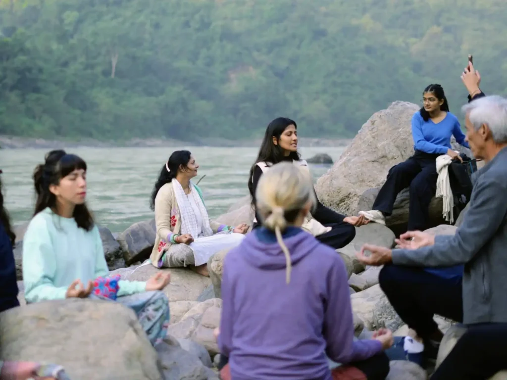 Home - New Design (Draft) 14 Yoga teacher training students sitting by the river during an excursion in Rishikesh